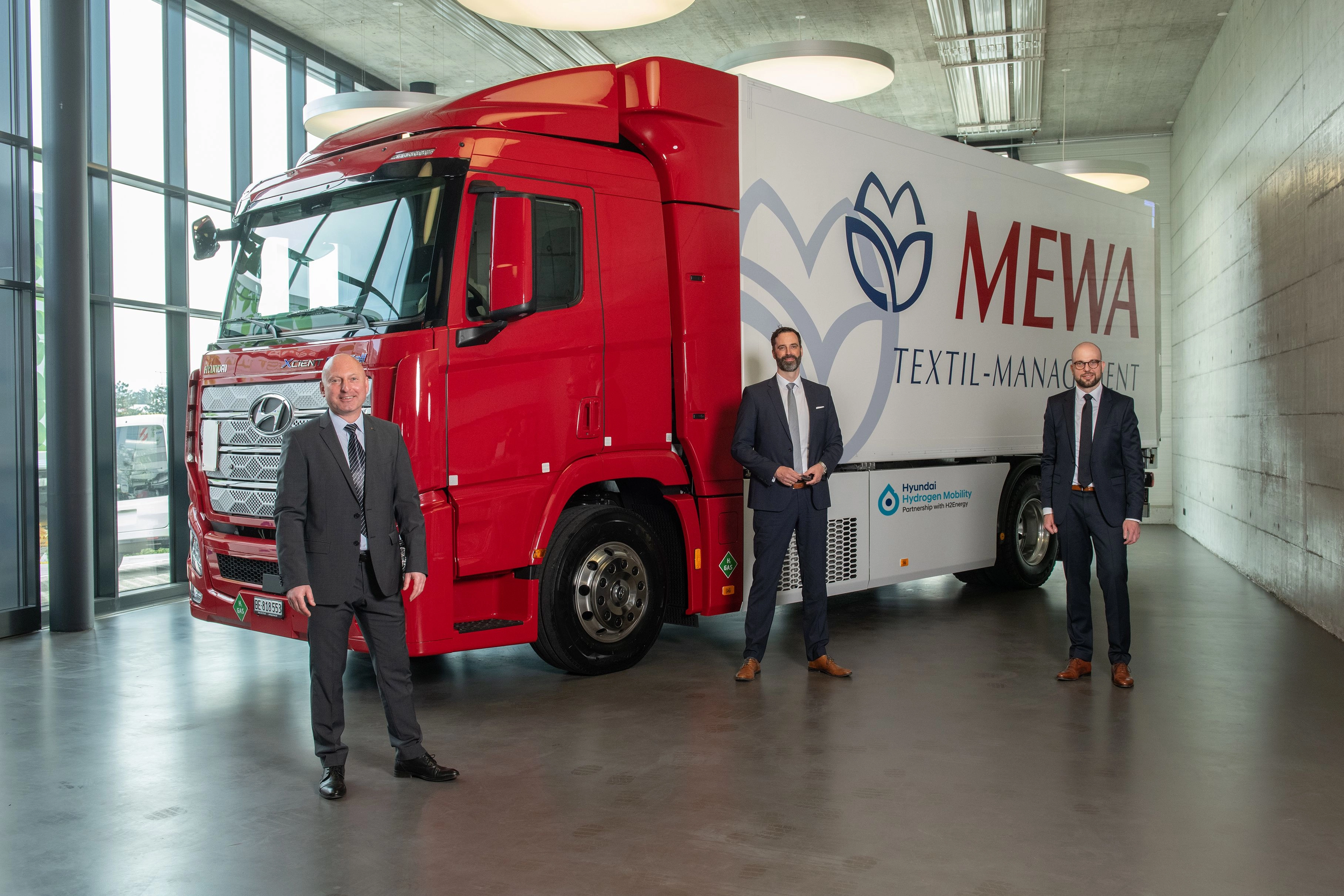 George Lazar, MEWA Zwitserland, Mark Freymüller, Hyundai HM, Kay Simon, MEWA Wiesbaden, bij de overhan-diging van de Hyundai Xcient Fuel Cell vrachtwagen op waterstof (v.l.n.r.)